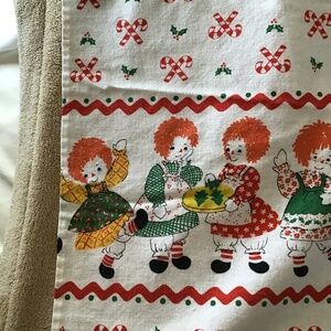 Raggedy Ann tablecloth Christmas theme.  Candy canes, holly. baking cookies.